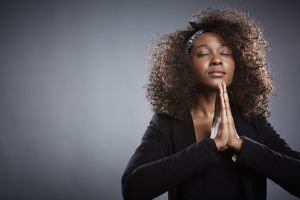 Studio portrait of young businesswoman praying