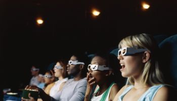 Large group of people watching movie in a movie theatre wearing 3D glasses