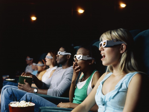 Large group of people watching movie in a movie theatre wearing 3D glasses