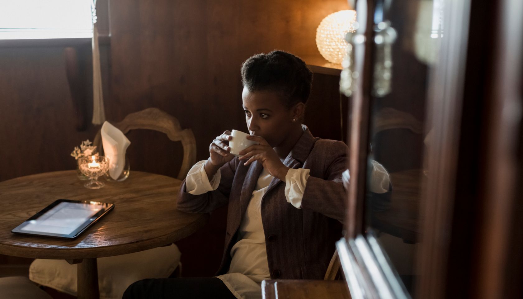 Pensive young woman sitting in a cafe drinking coffee