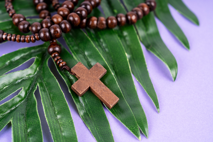 Rosary Beads on top of Palm Leaves Purple Background