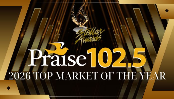 Praise 102.5 2026 Top Market of the Year award logo on a golden stage backdrop with spotlights.